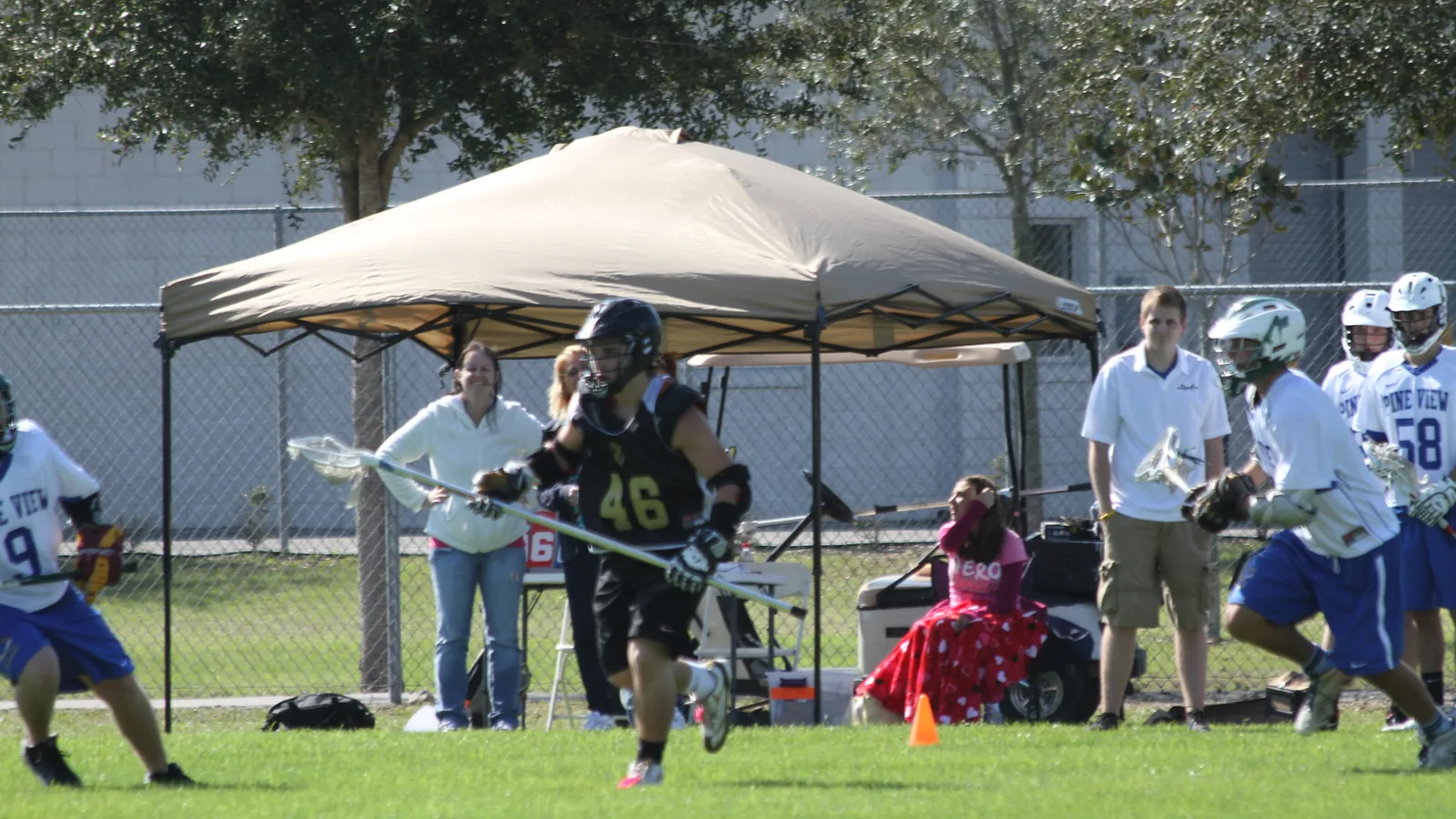 Spectators under a canopy beside the sports fields at Wesley Chapel District Park on Boyette Road
