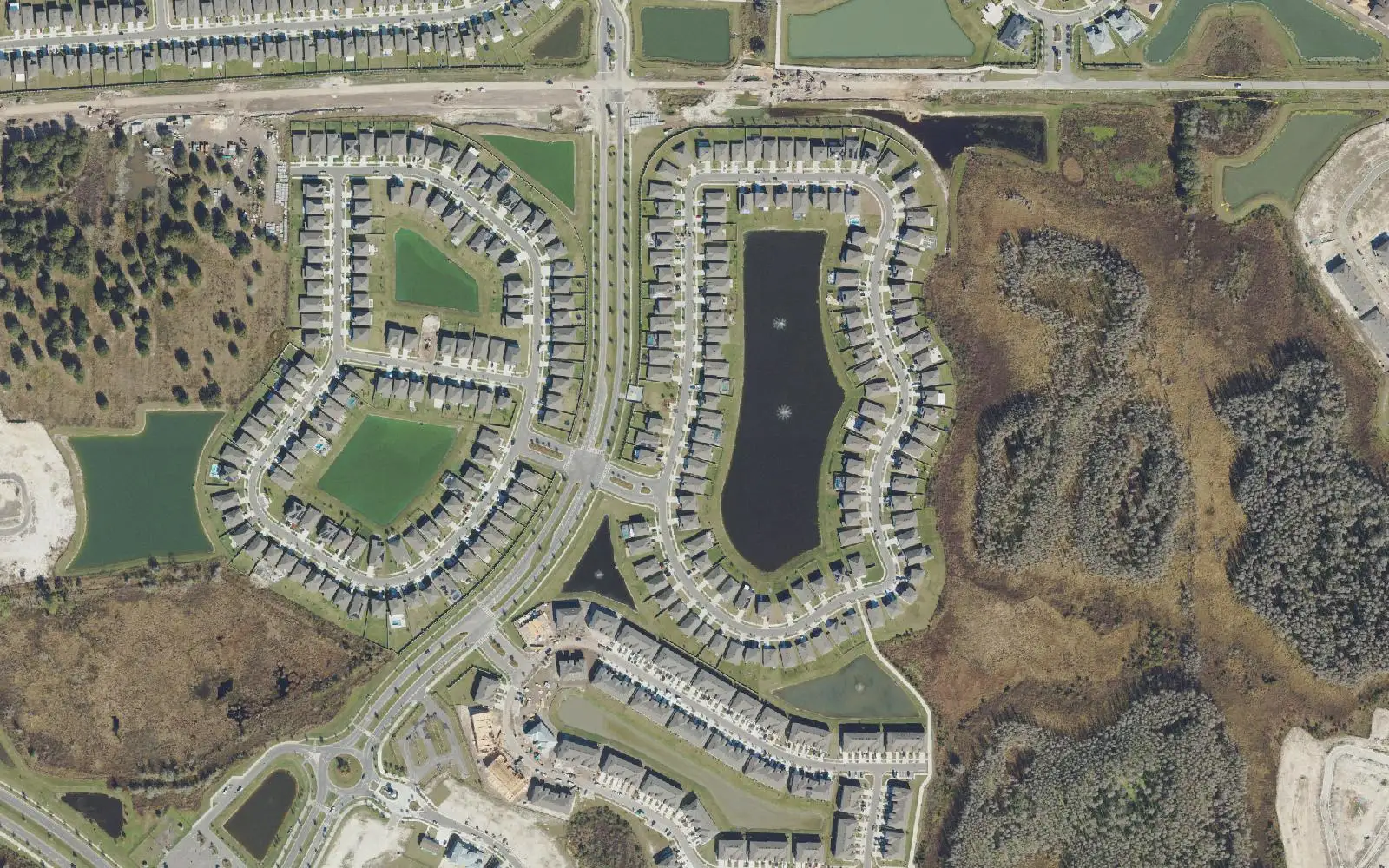 Rows of new homes around a long stormwater lake and open lawns in Epperson, with wetlands at right, seen from above.