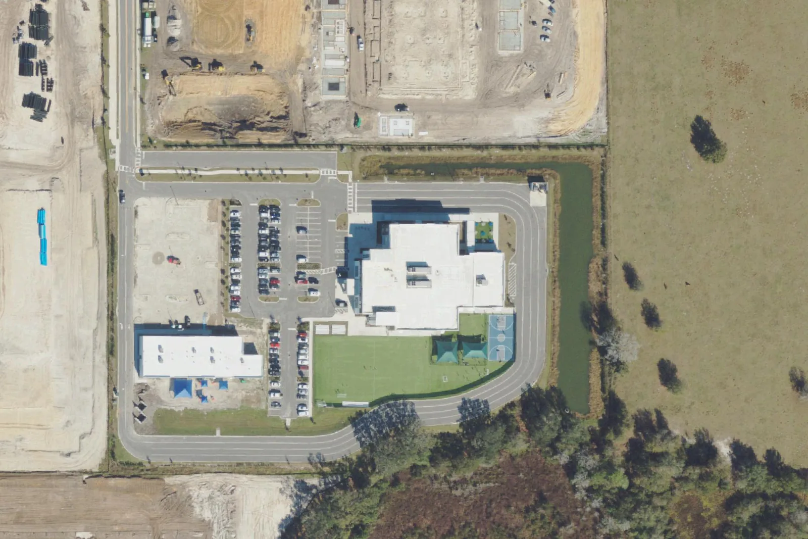 Innovation Preparatory Academy's school buildings, field and car loop on Avery Scope View, with construction around it, seen from the air in January 2023.