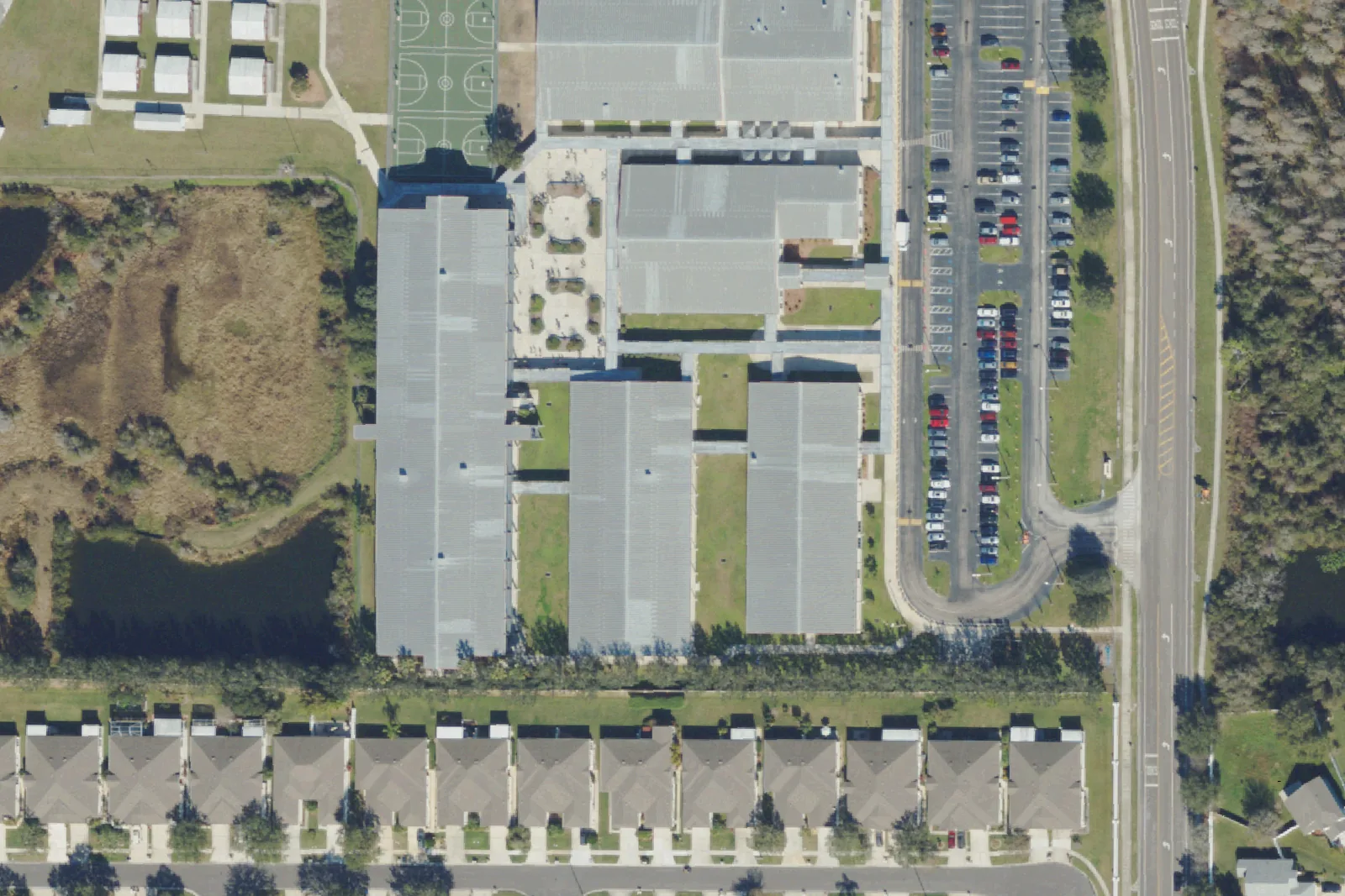 Dr. John Long Middle School's classroom wings and parking lot beside Mansfield Boulevard in Wesley Chapel, seen from the air.