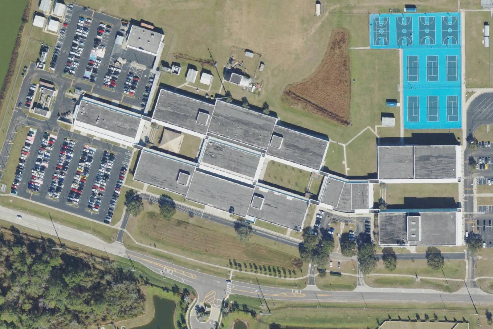 Wesley Chapel High School's classroom buildings, parking lots and tennis and basketball courts on Wells Road, seen from the air.