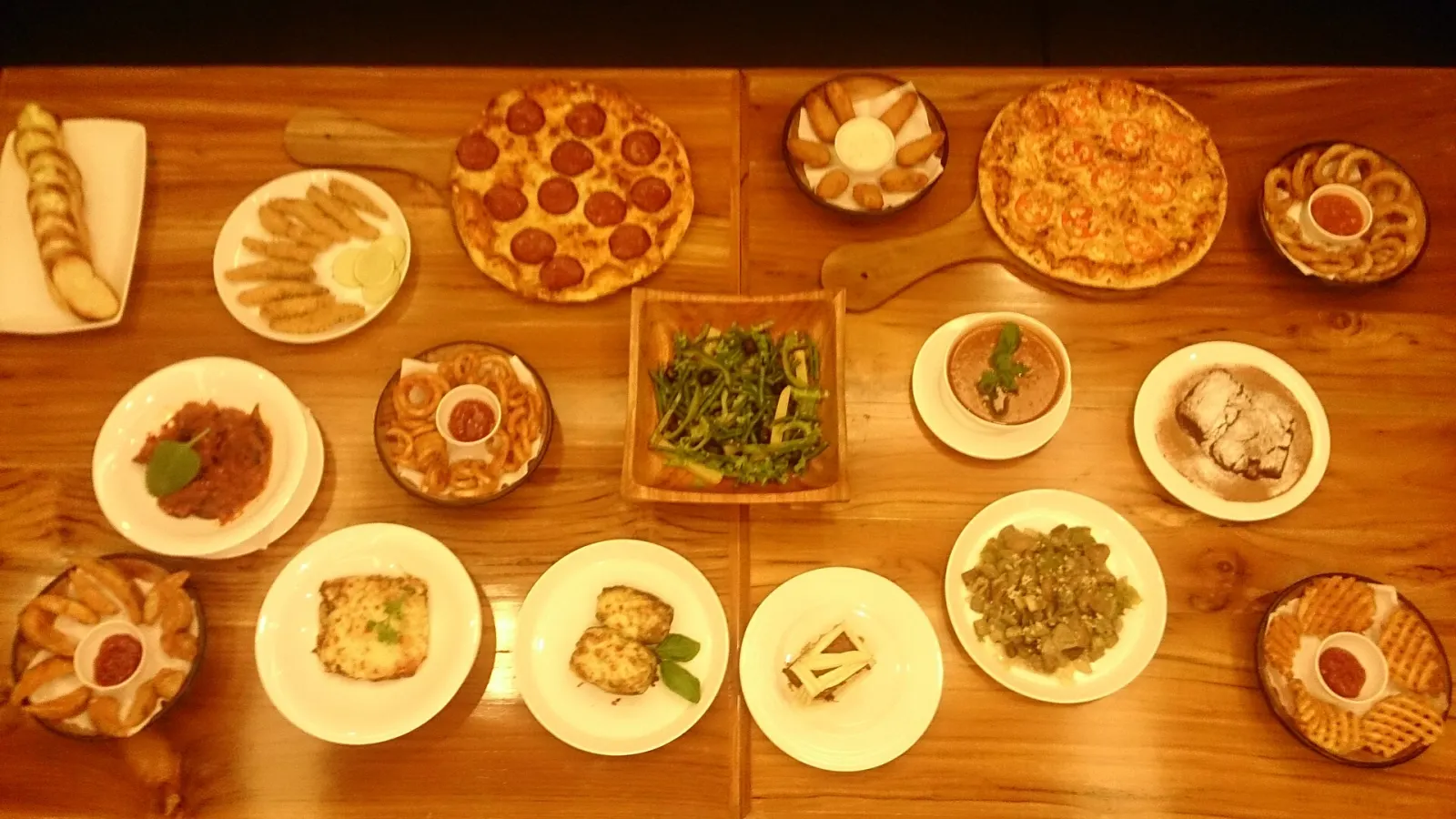 Pizzas, pasta, salads and fried sides shared on a restaurant table. The photo was not taken in Wesley Chapel.